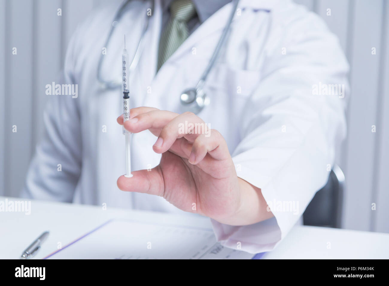 Doctor holding an injection needle in his outstretched hand. - Health care concept Stock Photo