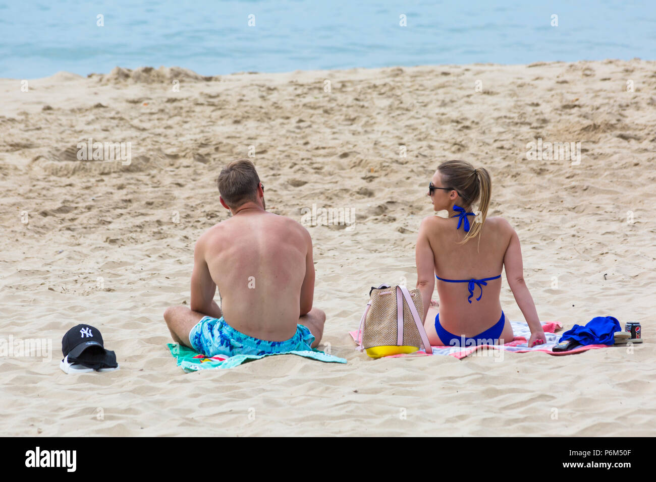 Bournemouth, Dorset, UK. 1st July 2018. UK weather: hazy sunshine, but still warm as thousands of sunseekers head to the beaches at Bournemouth to enjoy a day at the seaside. Couple sunbathing on the beach, back rear view. Credit: Carolyn Jenkins/Alamy Live News Stock Photo