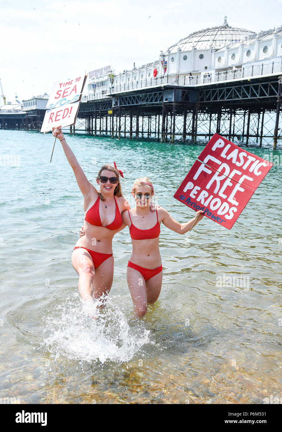 Brighton UK 1st July 2018 - Campaigners cool off in the sea on Brighton  beach on a beautiful hot sunny day after taking part in the Plastic Free  Period Products protest parade