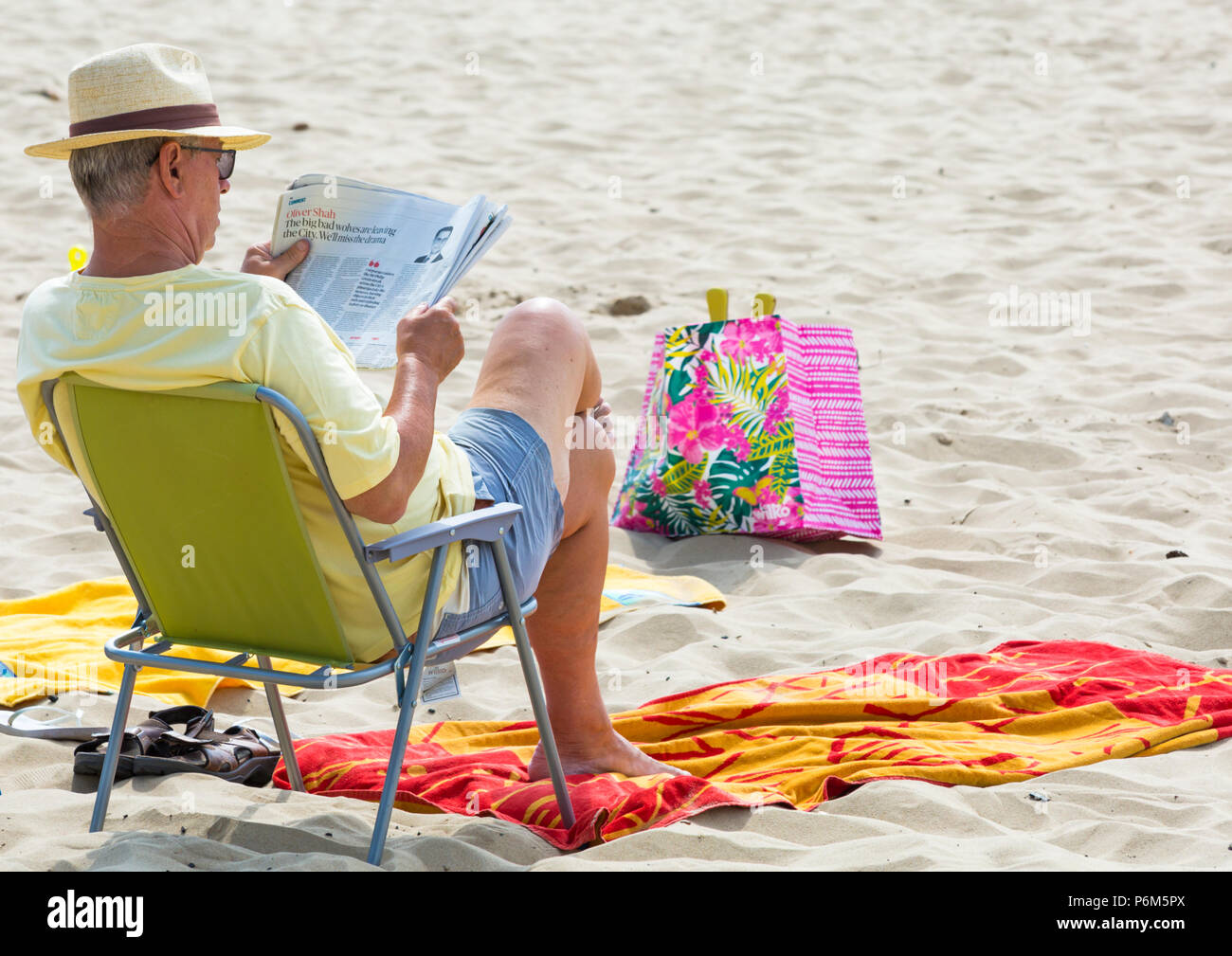 Bournemouth, Dorset, UK. 1st July 2018. UK weather: hazy sunshine, but still warm as thousands of sunseekers head to the beaches at Bournemouth to enjoy a day at the seaside. Man sitting in chair reading the Sunday Times newspaper. Credit: Carolyn Jenkins/Alamy Live News Stock Photo