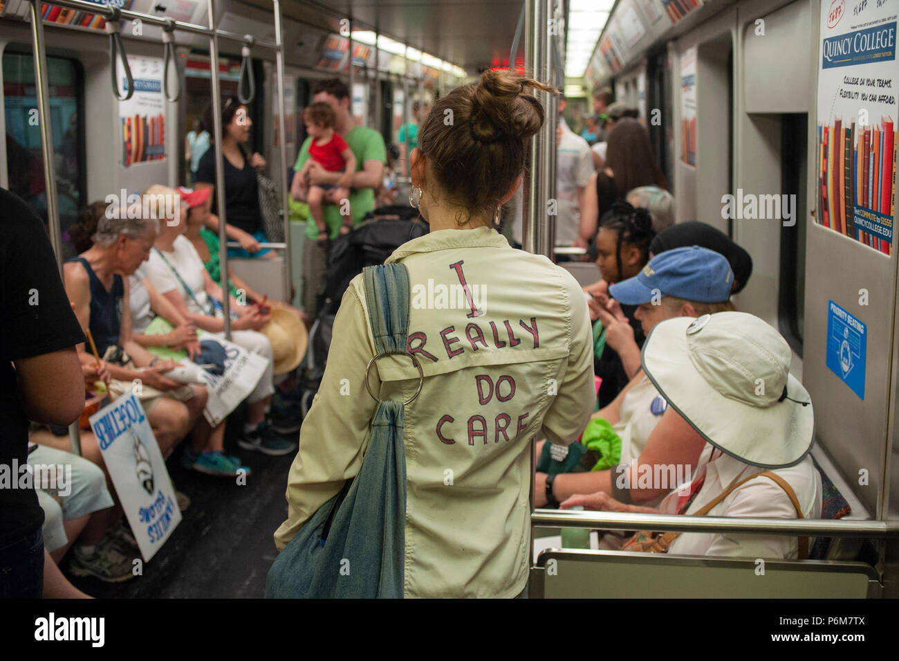 Boston, Massachusetts, USA. 30th June, 2018.  U.S. University Student wearing a coat mocking the Jacket that First Lady, Melania Trump wore before visiting a Texas detention shelter. The student and demonstrators are riding home on the Boston Metro after thousands gathered in central Boston, MA, during the Rally against Family Separation by the current United States administration. Rallies against U.S. President Donald Trump’s policy of the detention immigrants and immigrant families separated by ICE took place in more than 750 US cities on June 30th.  Credit: Chuck Nacke/Alamy Live News Stock Photo