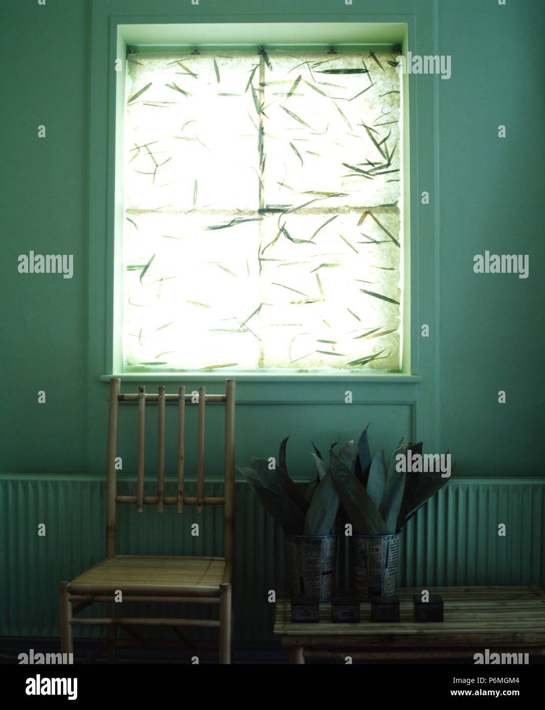 Bamboo chair below window with foliage patterned blind in simple dining