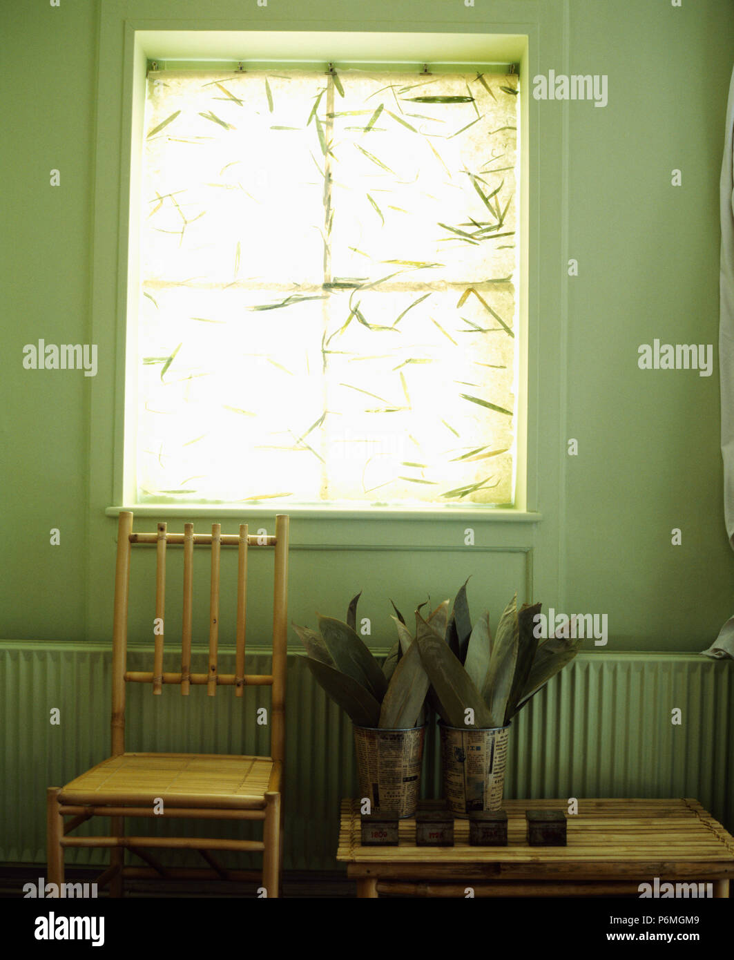 Bamboo chair below window with foliage patterned blind in simple dining