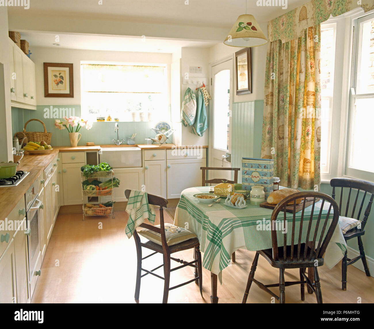 Old Wooden Chairs At Table With Green Cloth In Pale Green Kitchen