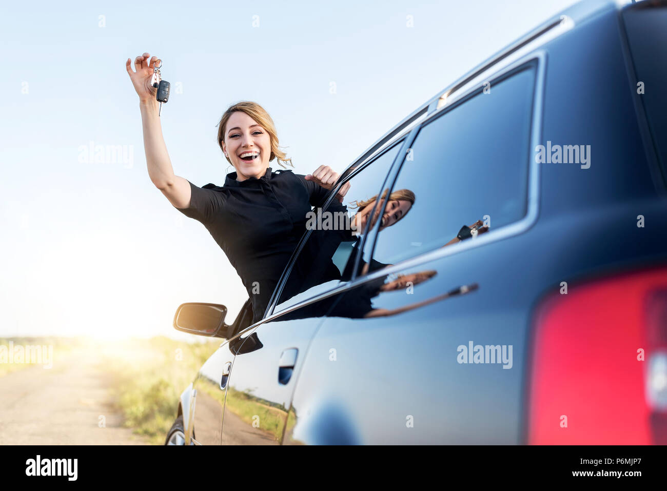 An attractive woman in a car holds a car key in her hand. Stock Photo