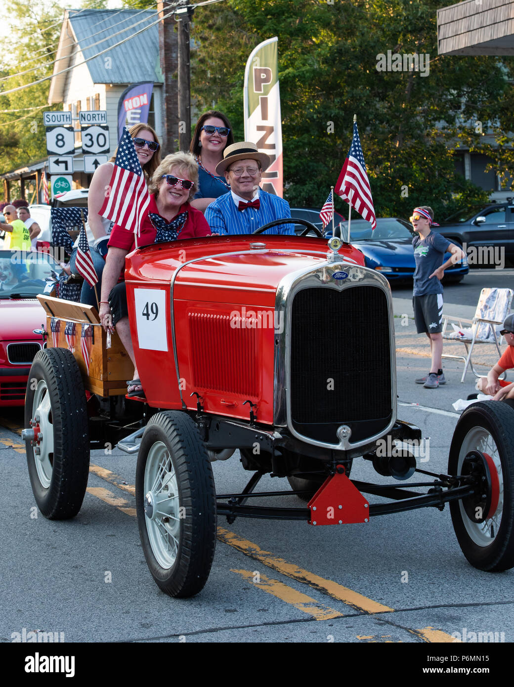 A fancy orange 1931 Ford Model A Doodlebug Tractor driving in the 4th