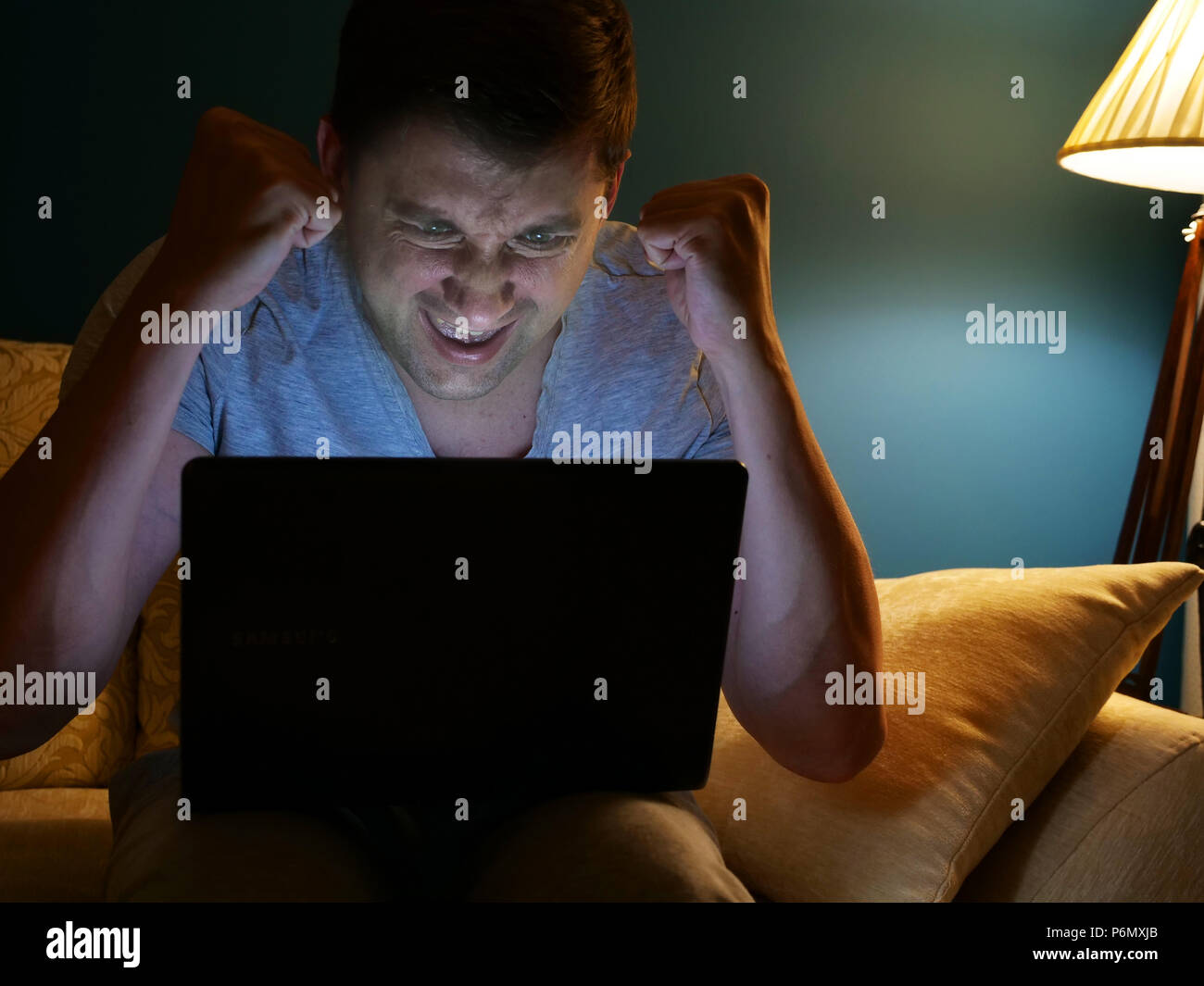 Happy man watching something on a laptop. Winning. Evening activities at home. Stock Photo