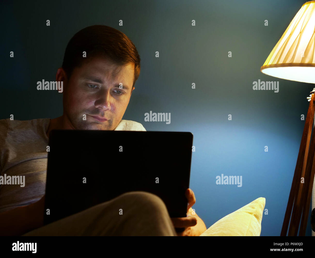 Man on a sofa using laptop. Evening at home. Stock Photo