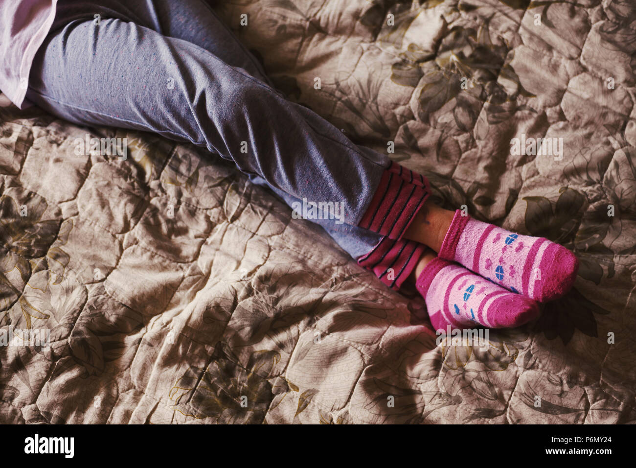 Legs of a small girl resting on bed. Stock Photo