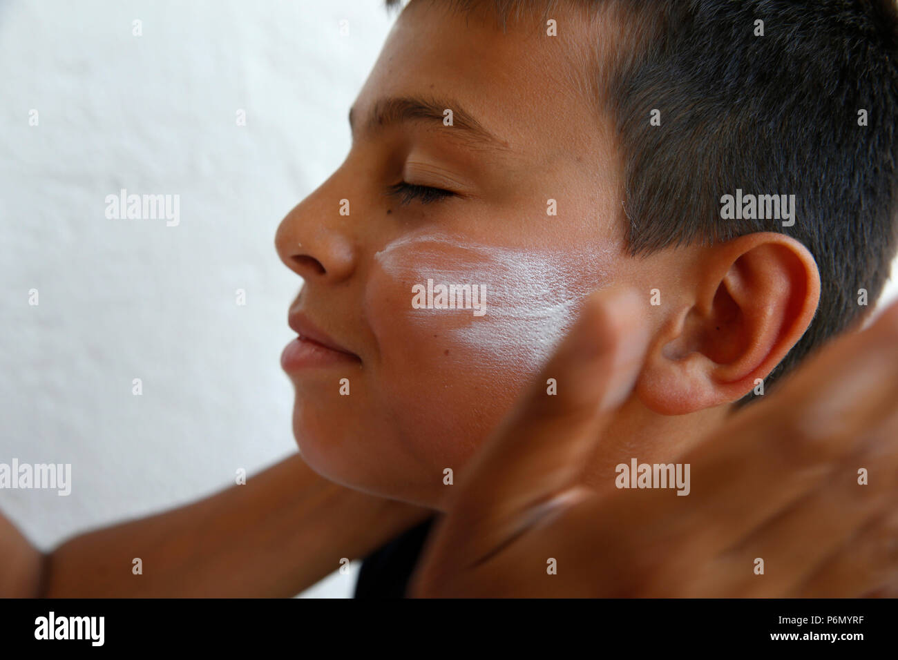 Mother putting sun protection cream on her son's face in Salento, Italy. Stock Photo