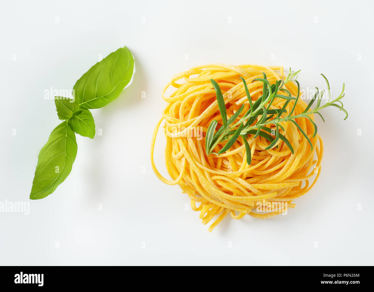 bundle of spaghetti pasta and fresh herbs on white background Stock Photo