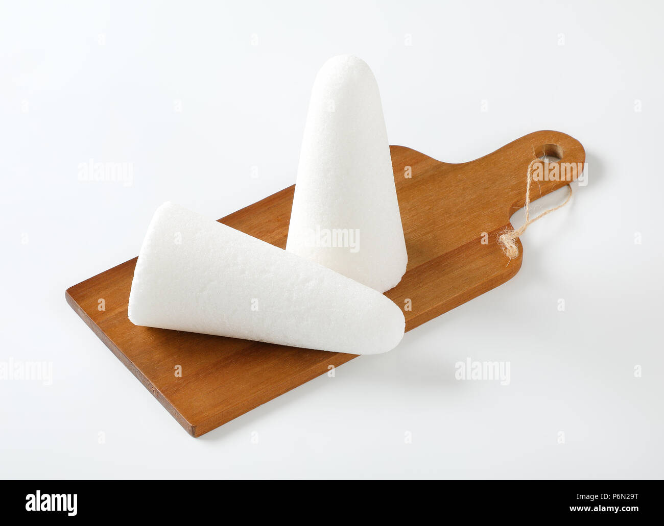 two white sugar loaves or cones on wooden cutting board Stock Photo