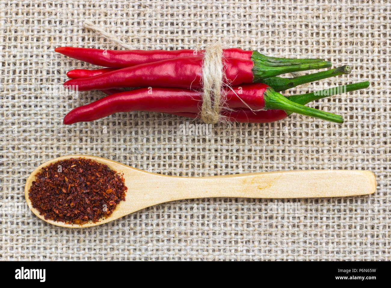Closeup top view of red chili pepper, tied with braid and spoon on