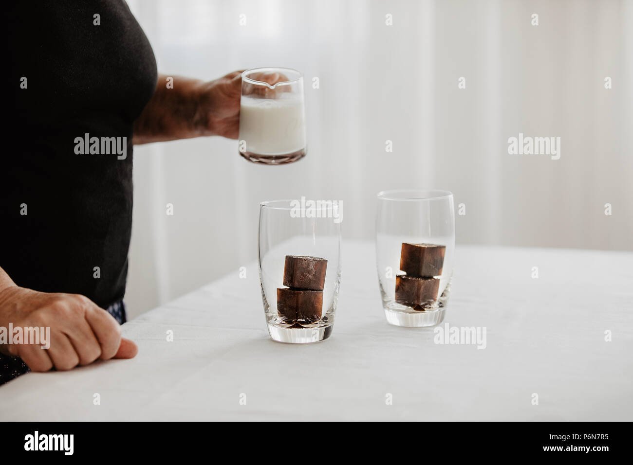 Woman preparing iced coffee. Frozen coffee ice cubes in a glass poured
