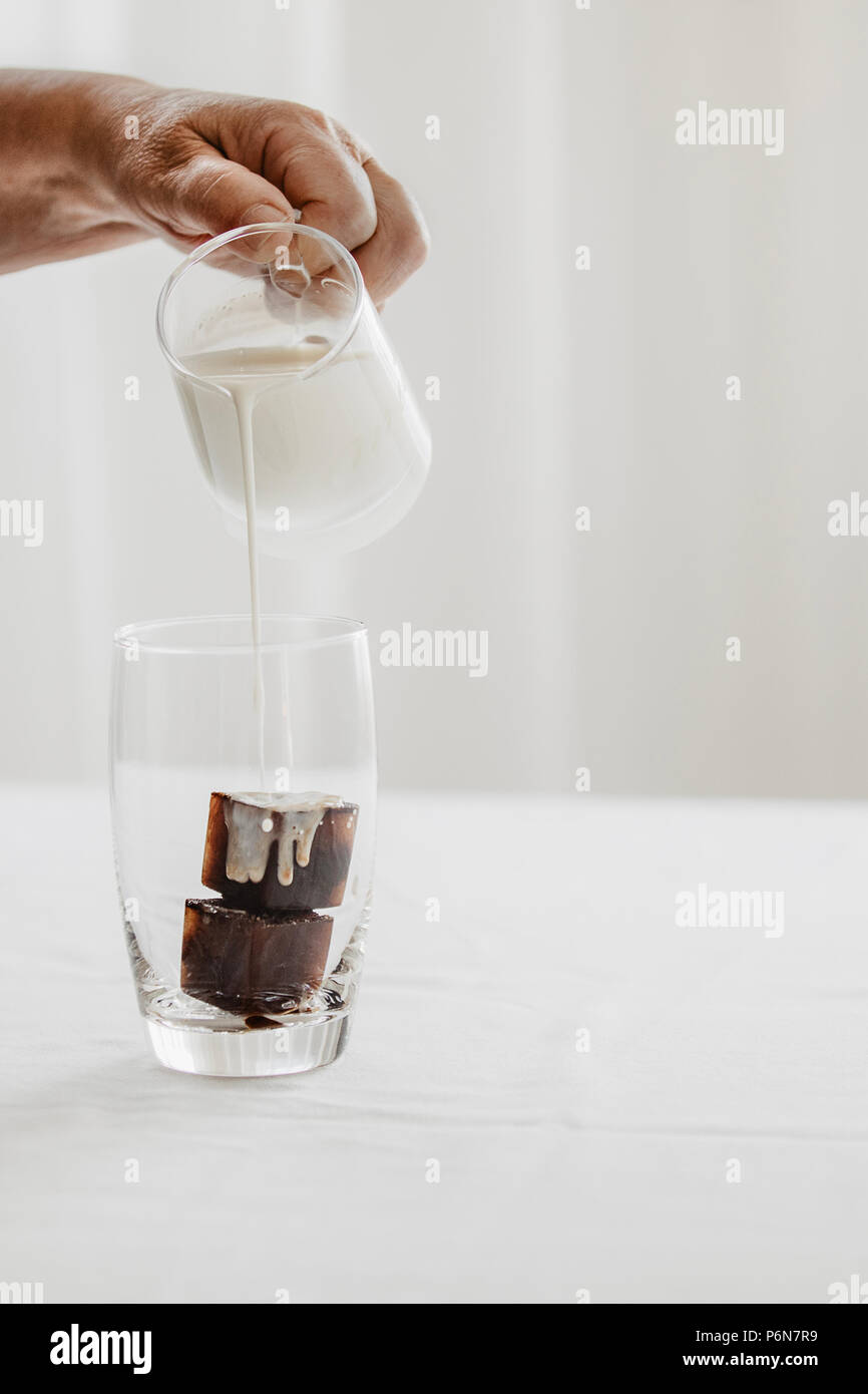 https://c8.alamy.com/comp/P6N7R9/woman-preparing-iced-coffee-frozen-coffee-ice-cubes-in-a-glass-poured-with-milk-to-make-a-refreshing-summer-drink-white-background-body-parts-P6N7R9.jpg