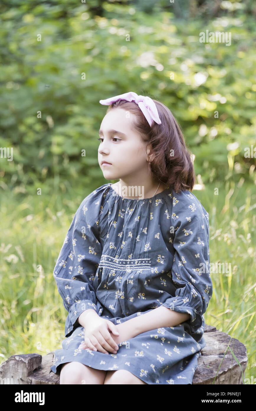 little girl is sitting on a stump in the forest, a lost child portrait ...