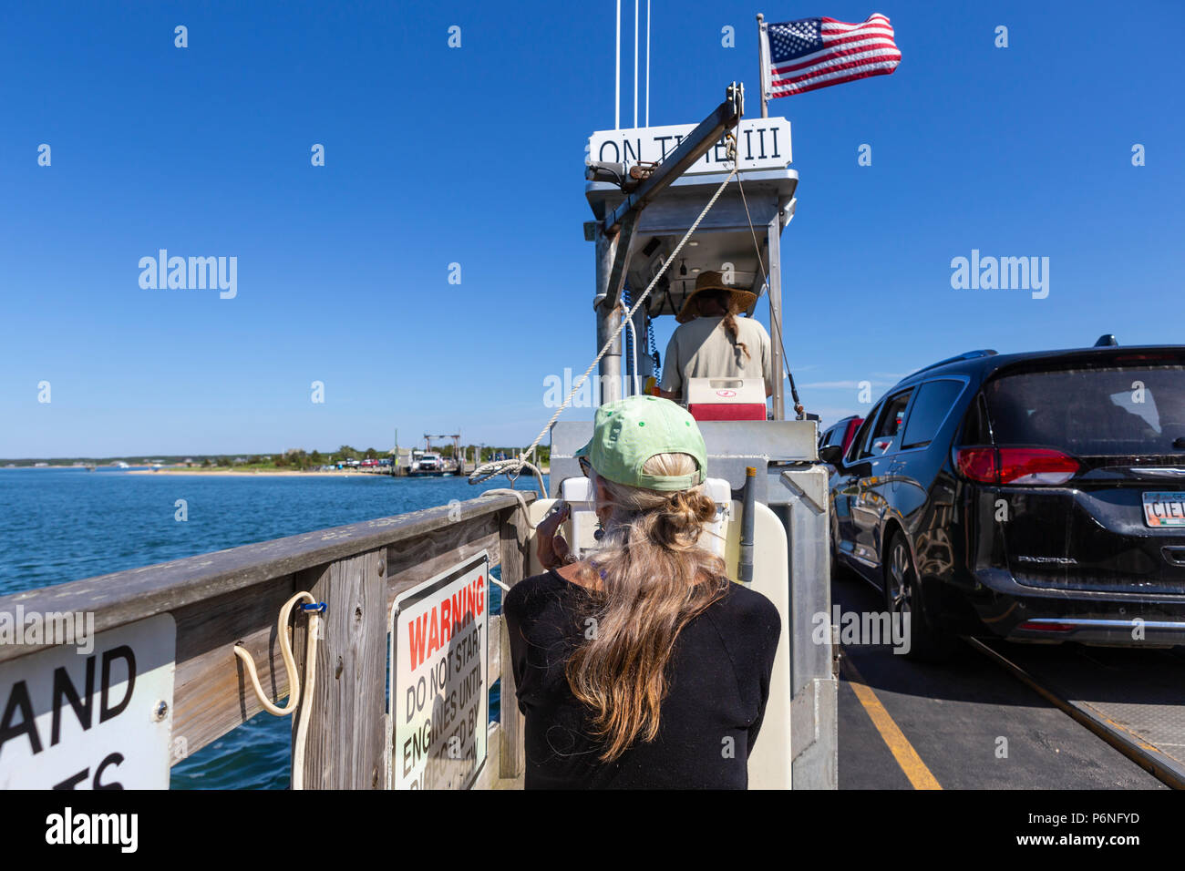 A woman enjoys the view from the Chappy Ferry on the short ride to Chappaquiddick Island from downtown Edgartown, Massachusetts on Martha's Vineyard. Stock Photo