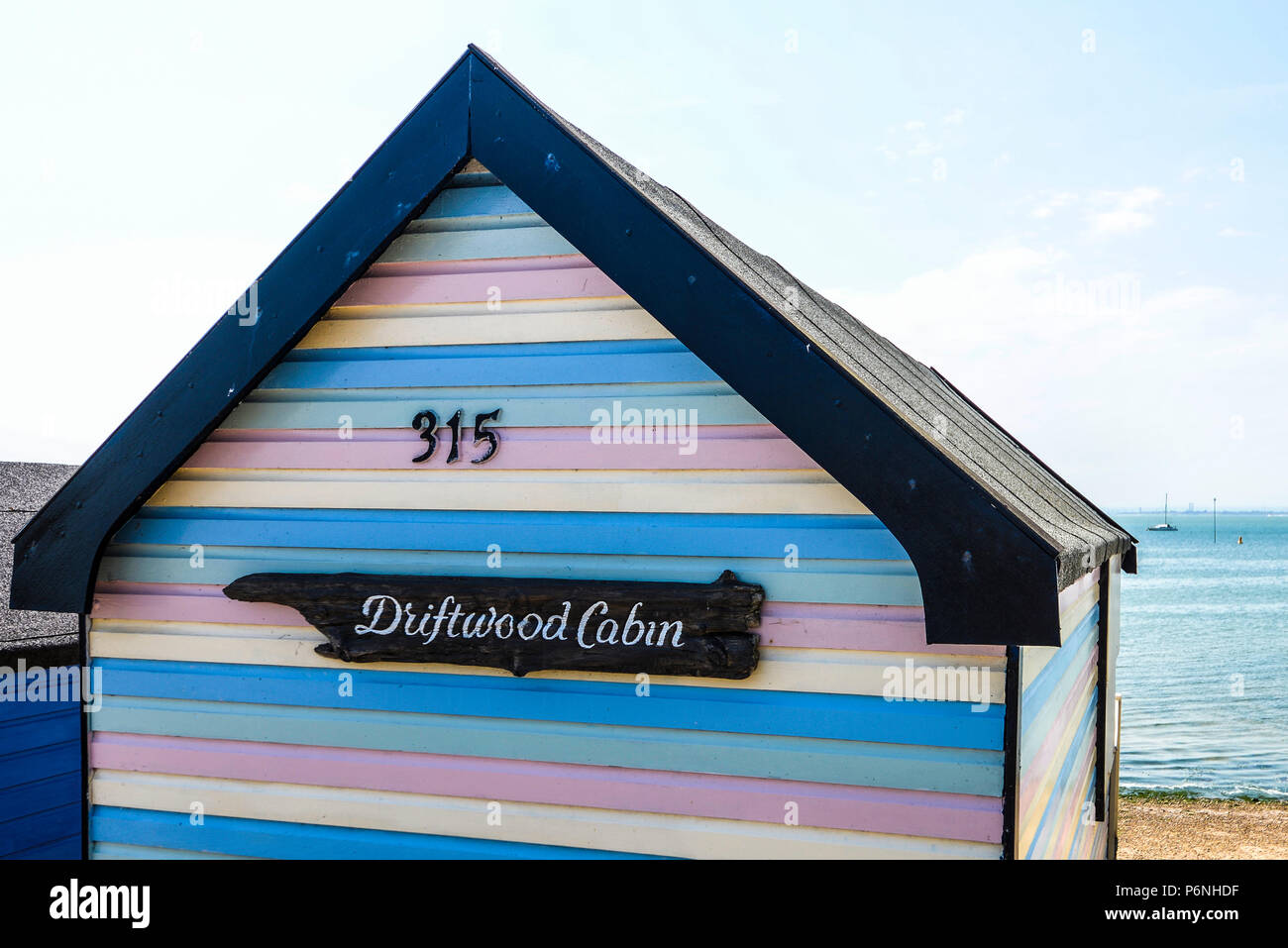 Driftwood Cabin. Multi coloured colourful stripey beach hut at Thorpe Bay, Southend on Sea, Essex, UK. Painted wood beach hut. Pastel colours Stock Photo