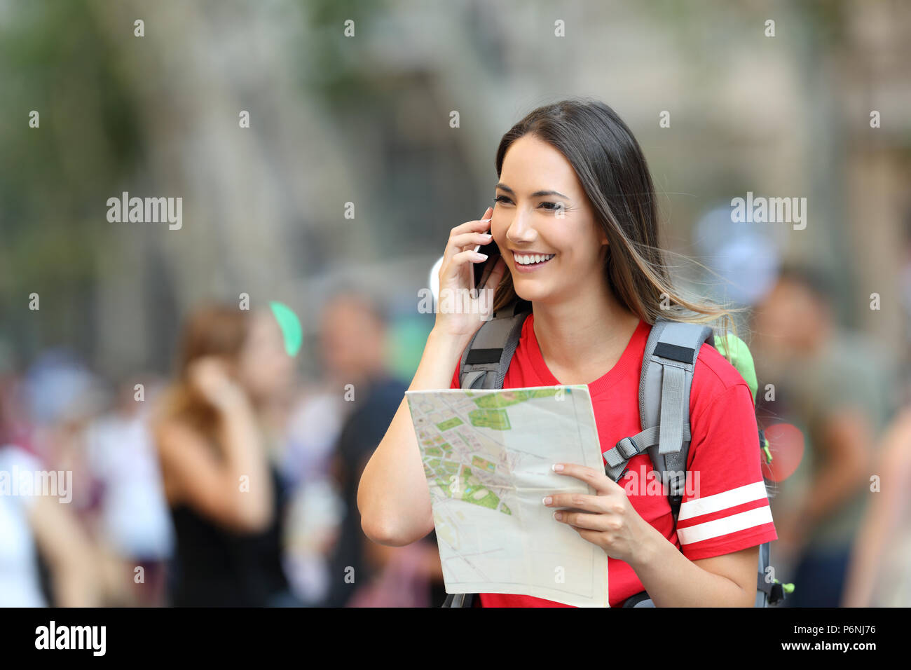 Happy teen tourist talking on phone holding a map walking on the street Stock Photo