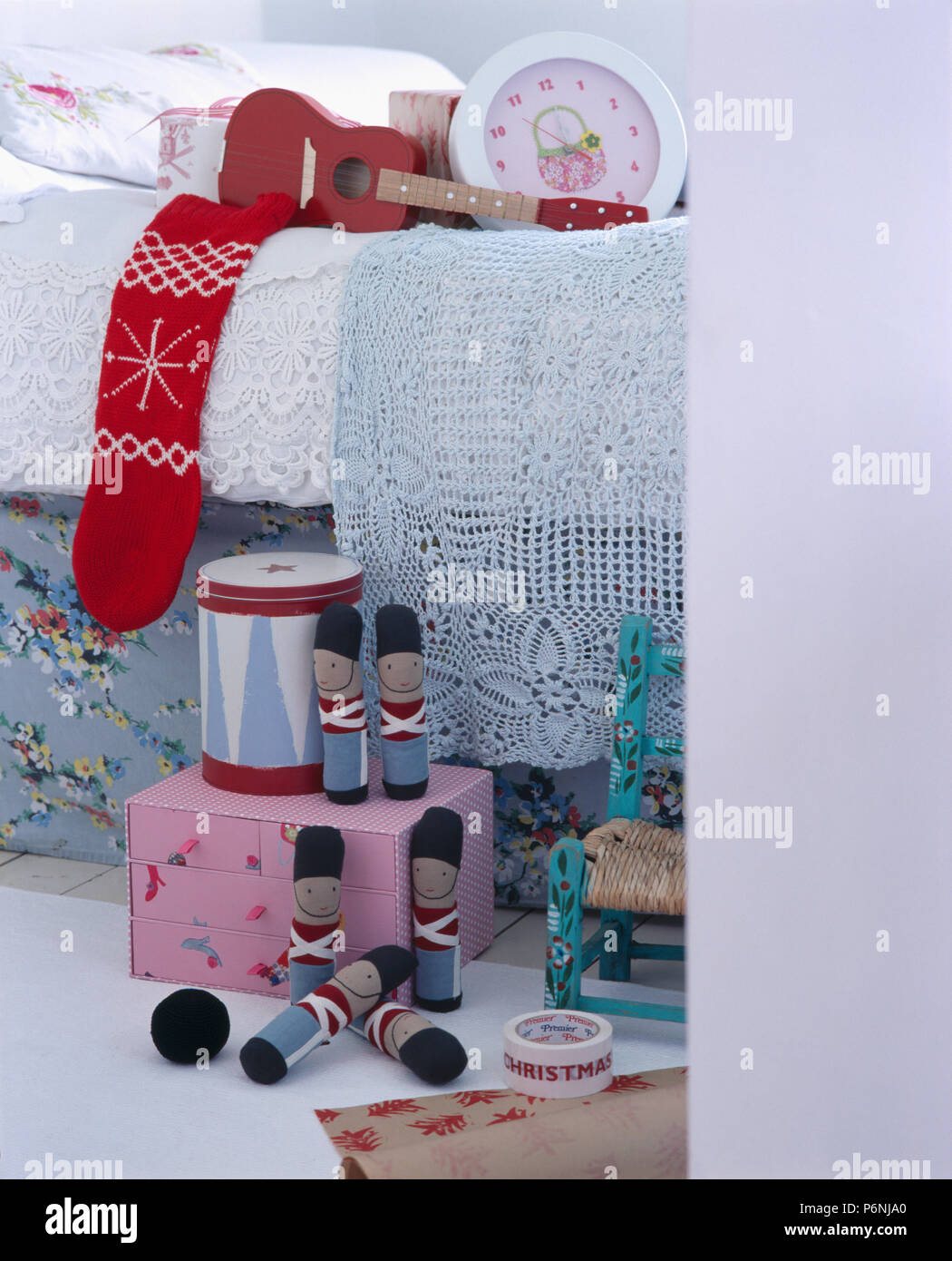 Close-up of wooden toy soldiers on box below child's bed with red woollen Christmas stocking Stock Photo