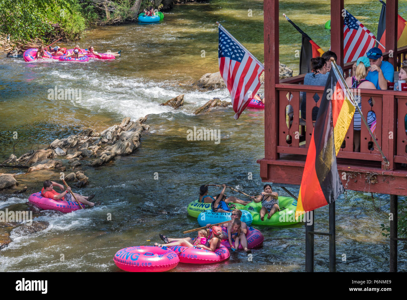 Diners enjoying lunch in downtown Helen, Georgia overlooking the Chattahoochee River where families enjoy a day of tubing in the cold mountain stream. Stock Photo