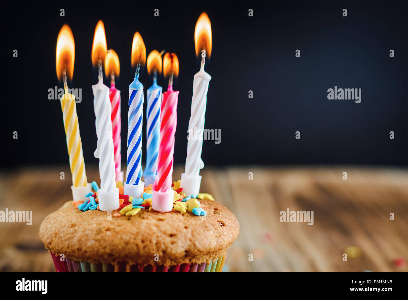 cupcake with lighted festive candles on wooden background with copy