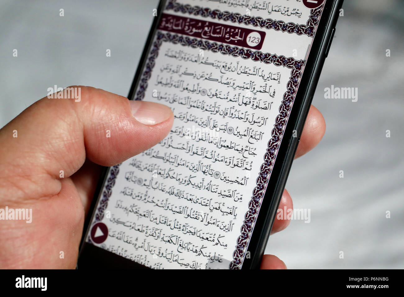 Man reading an electronic Quran on a smartphone. Stock Photo
