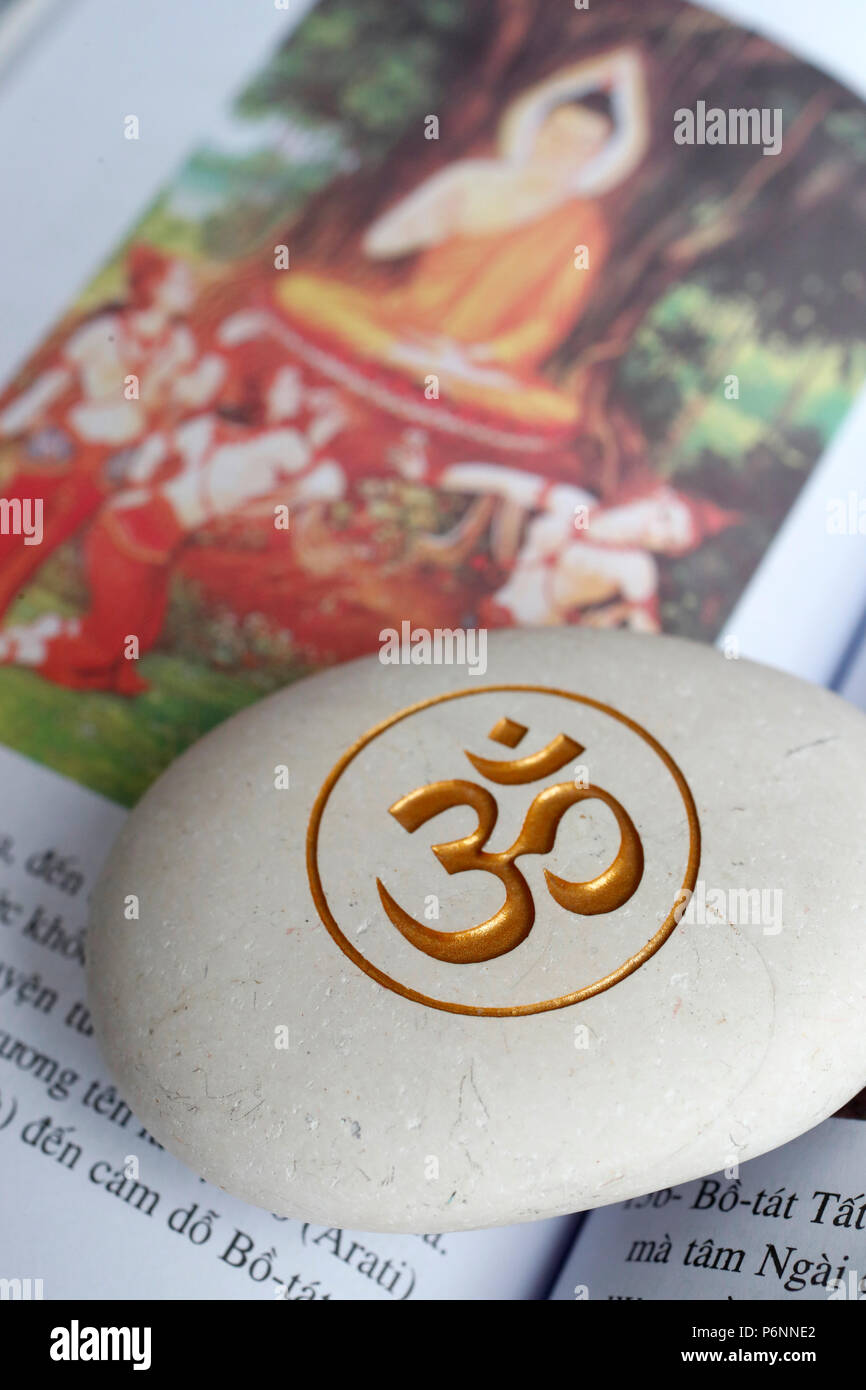 The Om or Aum symbol of Hinduism and Buddhism on a white stone. Book of the life of Buddha. Stock Photo