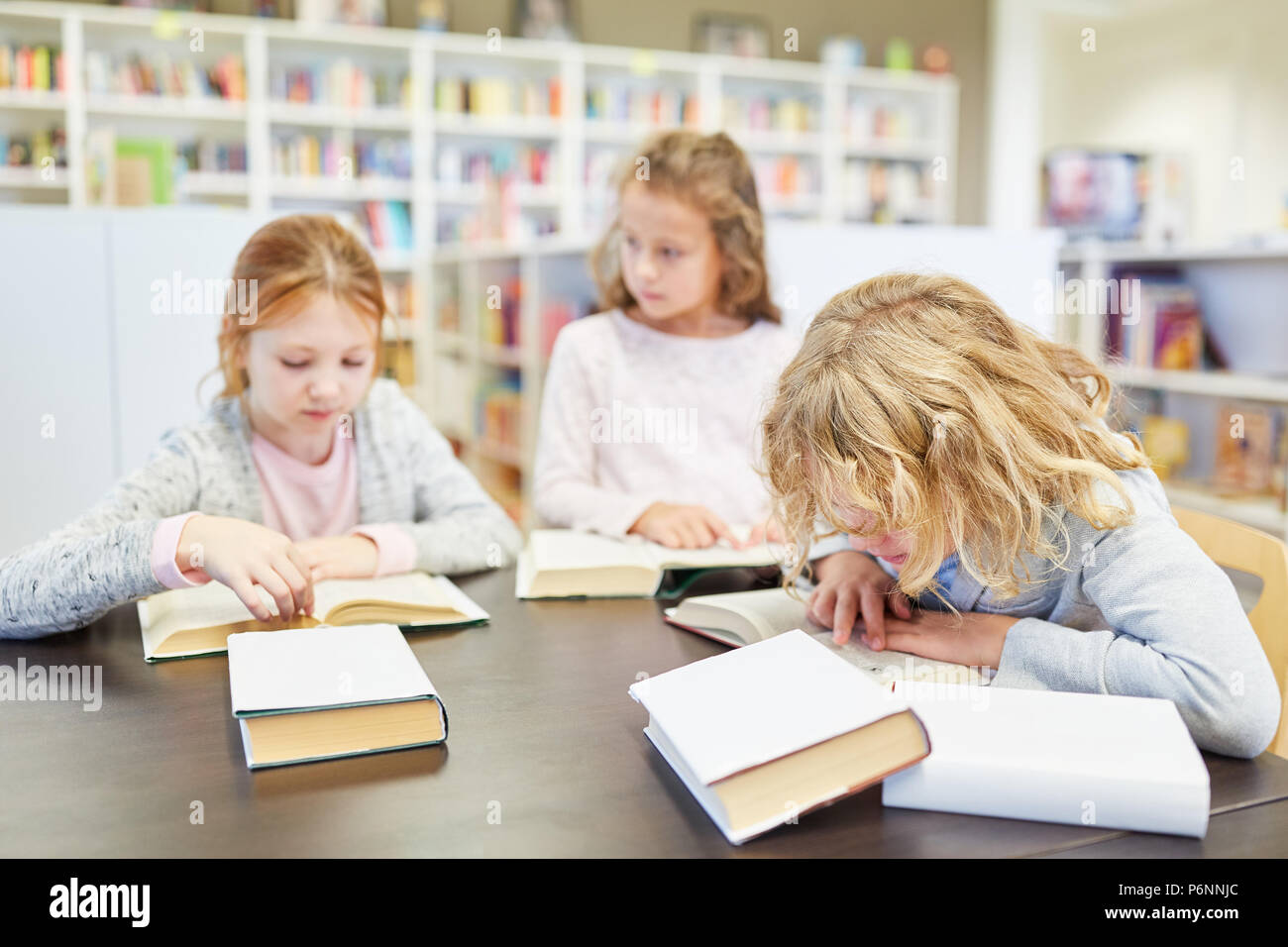 Three students in a study group reading concentrated in their books Stock Photo