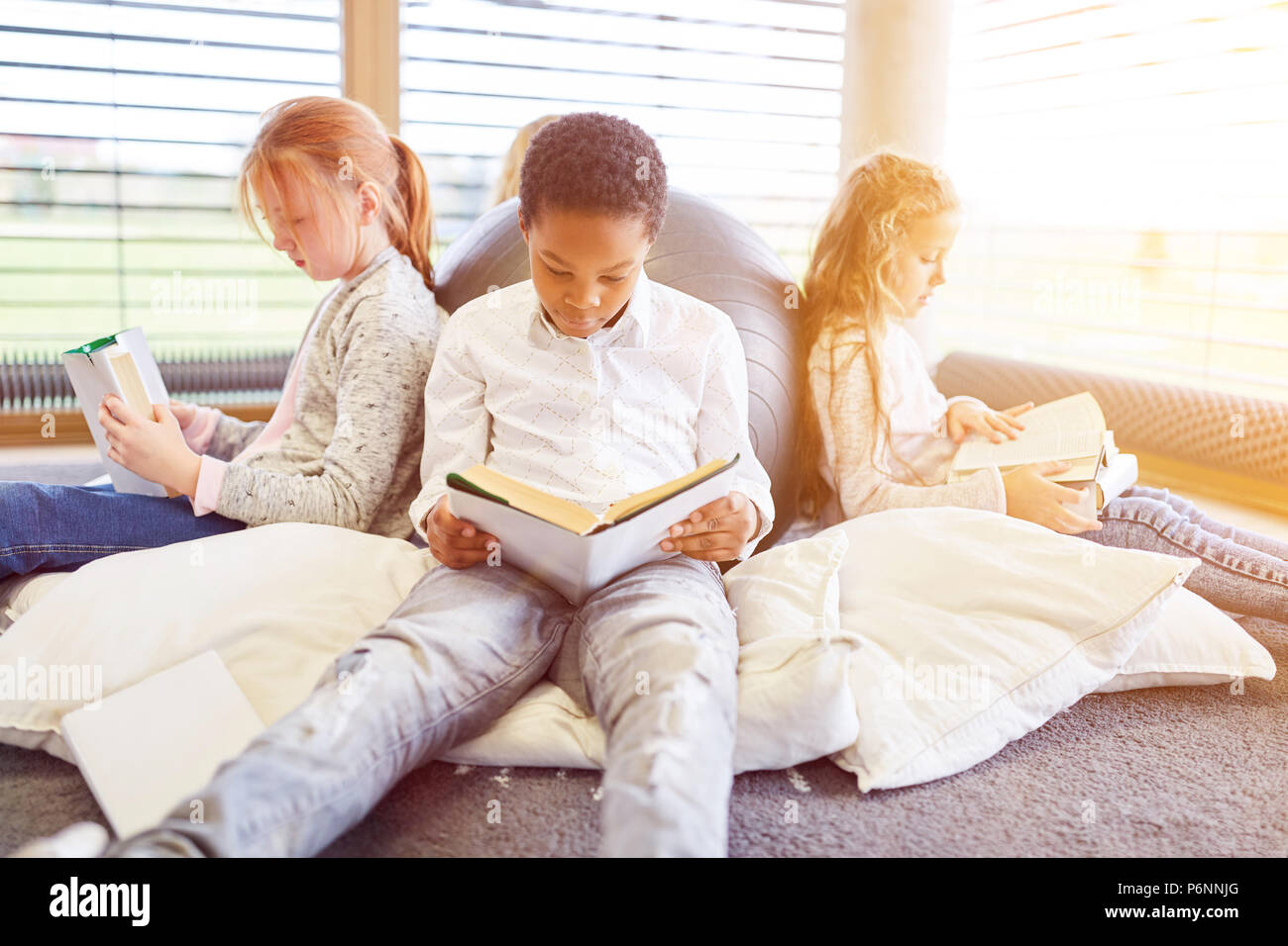 Group of children together read books in the reading corner of a library Stock Photo