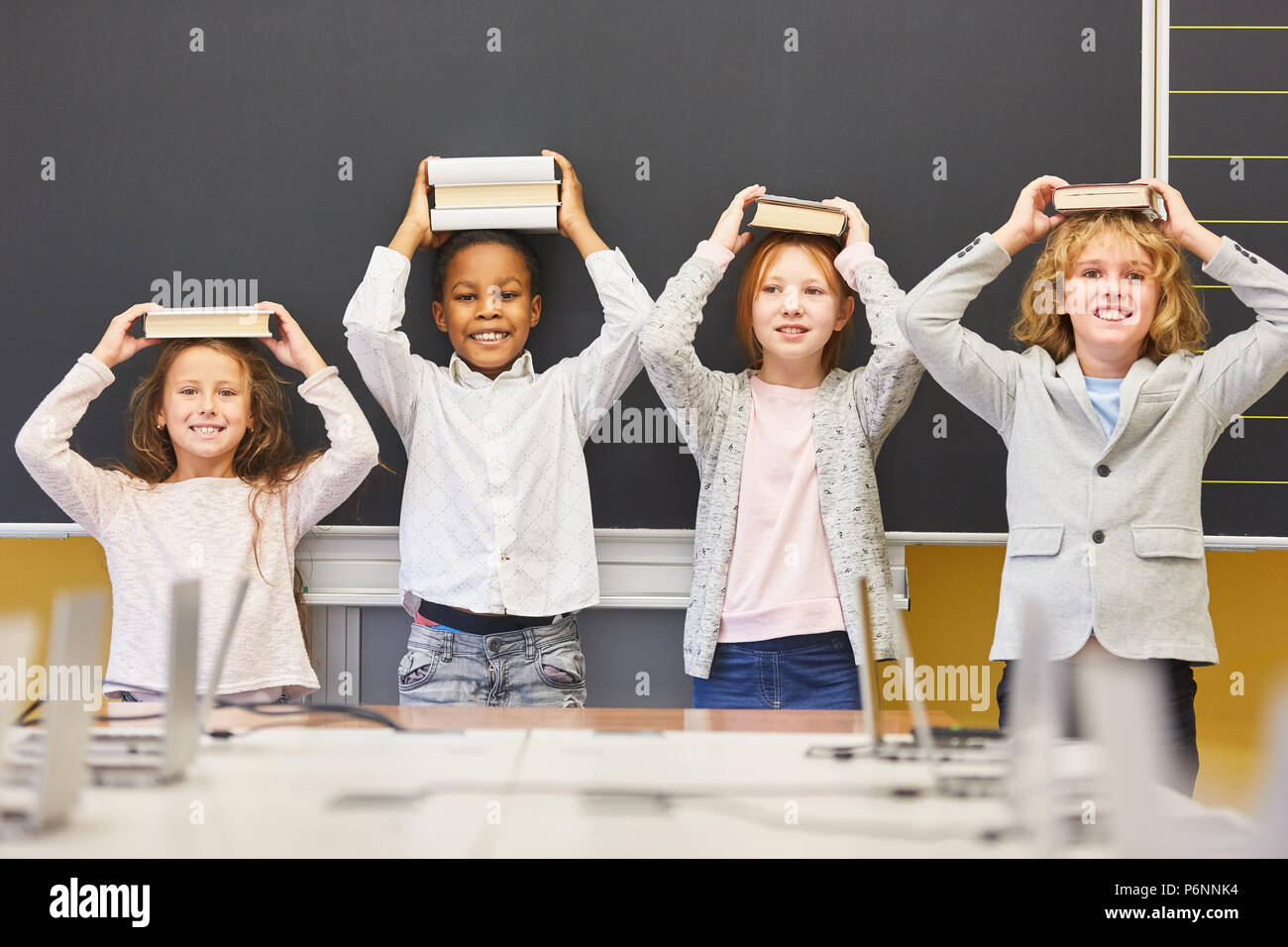Group of children in elementary school make mischief with books on their heads Stock Photo