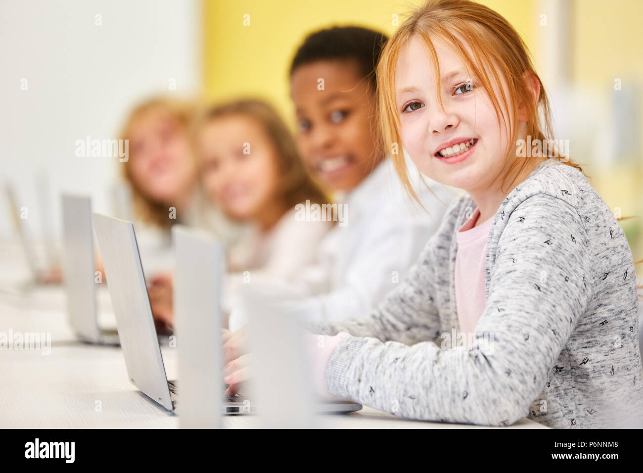 Girl is learning in primary class computer class with friends at laptop ...