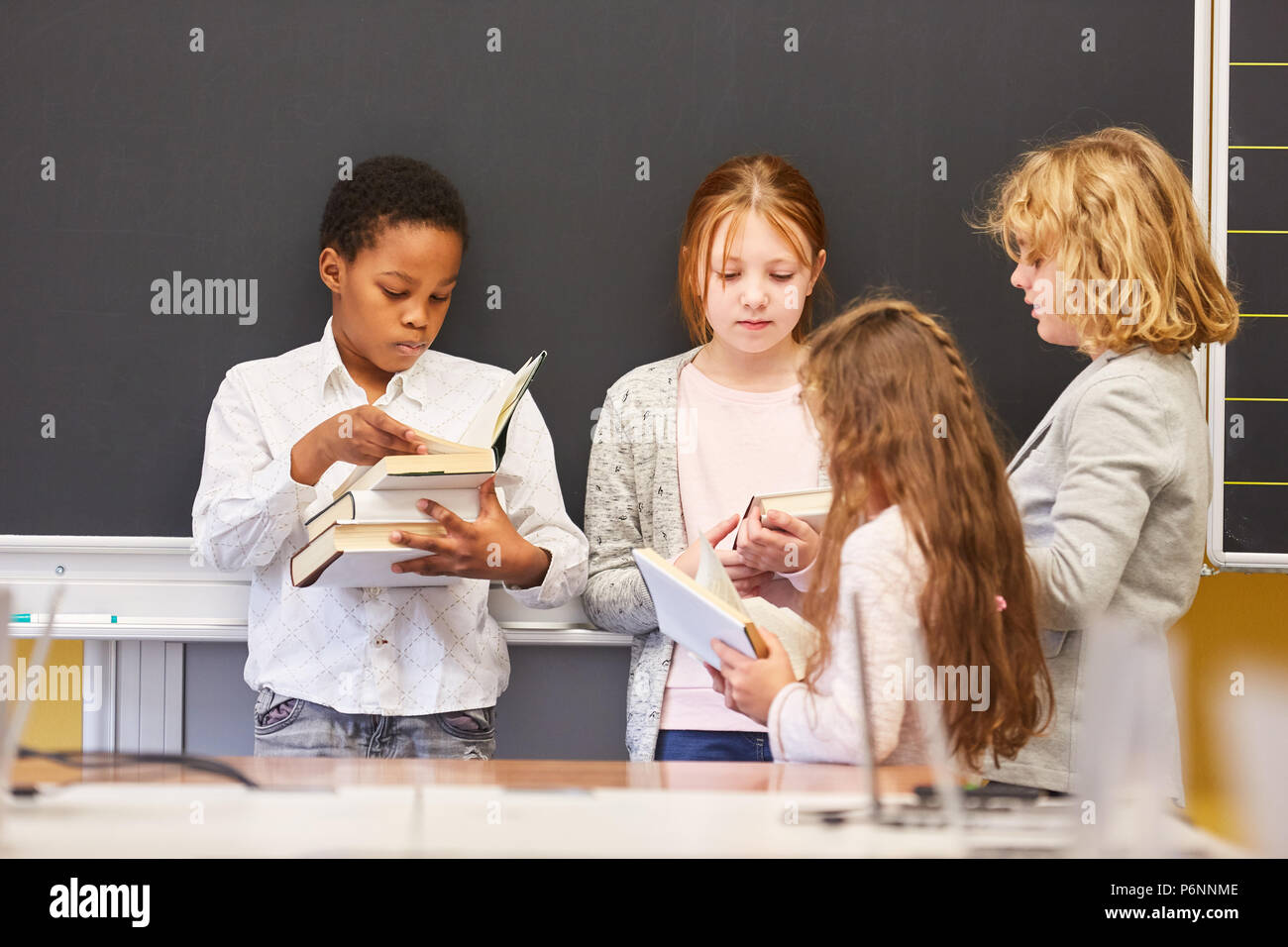 Group of children together read books in a primary school study group Stock Photo