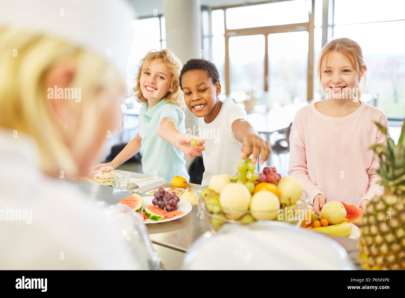 Group of multicultural kids at the fruit buffet at the cafeteria in elementary school Stock Photo