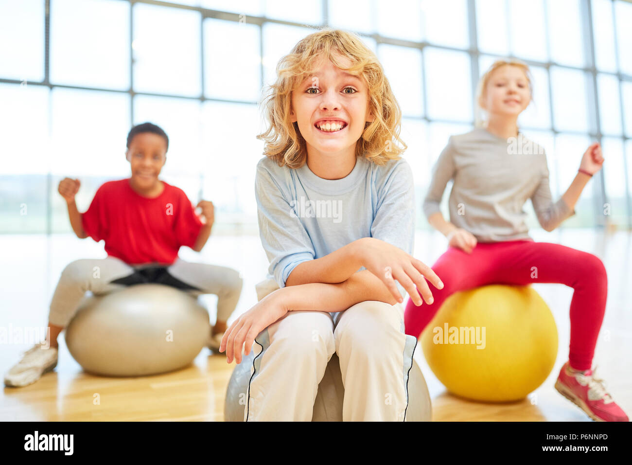 Three kids in primary school physical education with bouncy ball in the gym Stock Photo