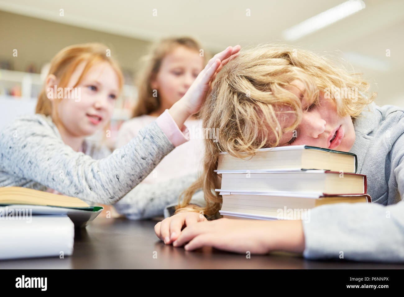 Boy as a student sleeps exhausted on his homework at school Stock Photo