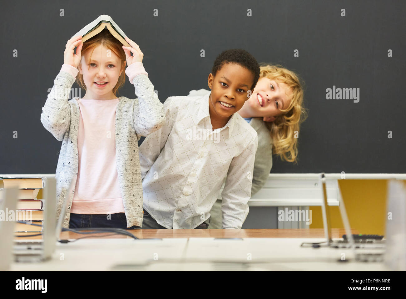 Children have fun in elementary school in class in front of the empty blackboard Stock Photo