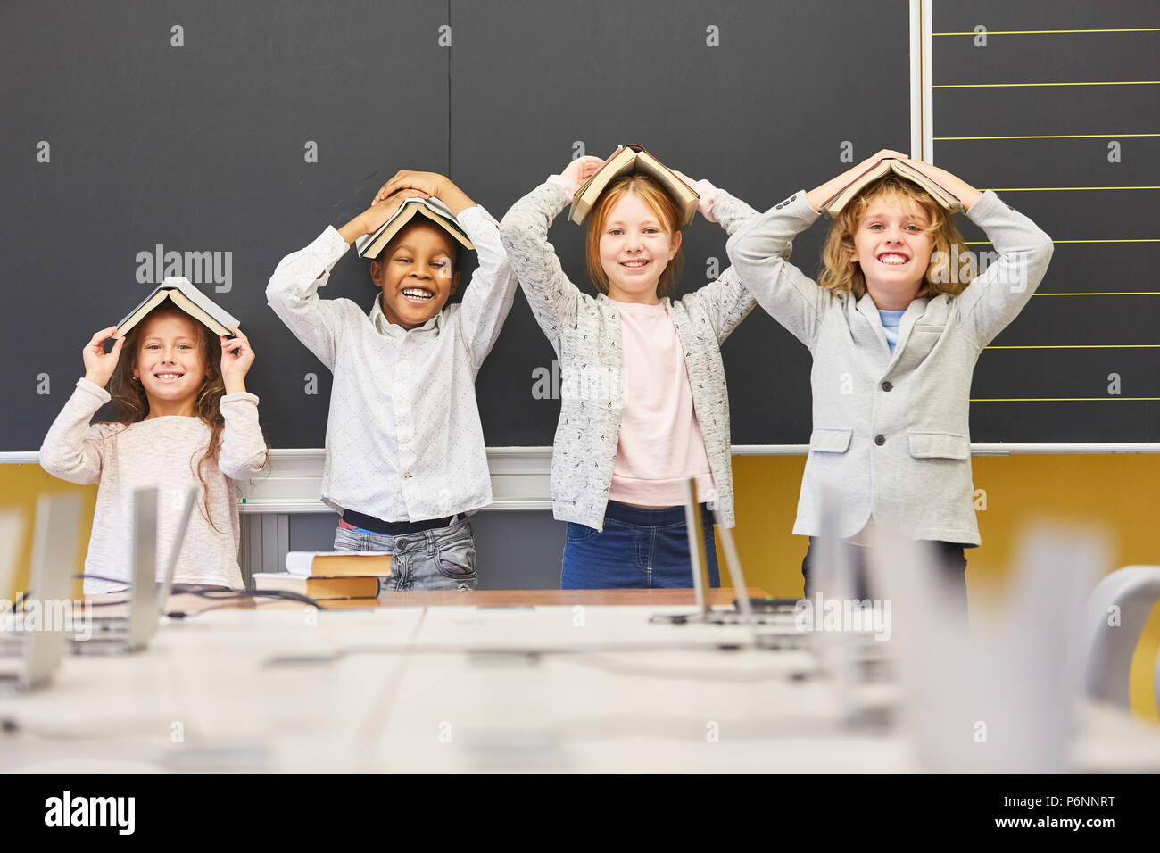 Kids in elementary school are laughing and silly with books in class Stock Photo