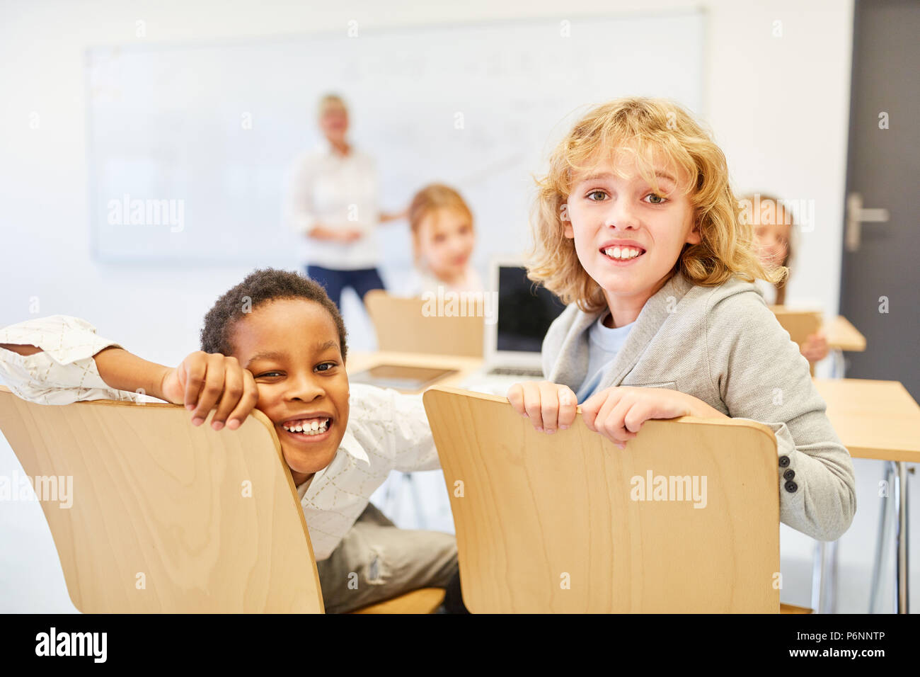Two boys as friends in the classroom of a multicultural elementary school Stock Photo