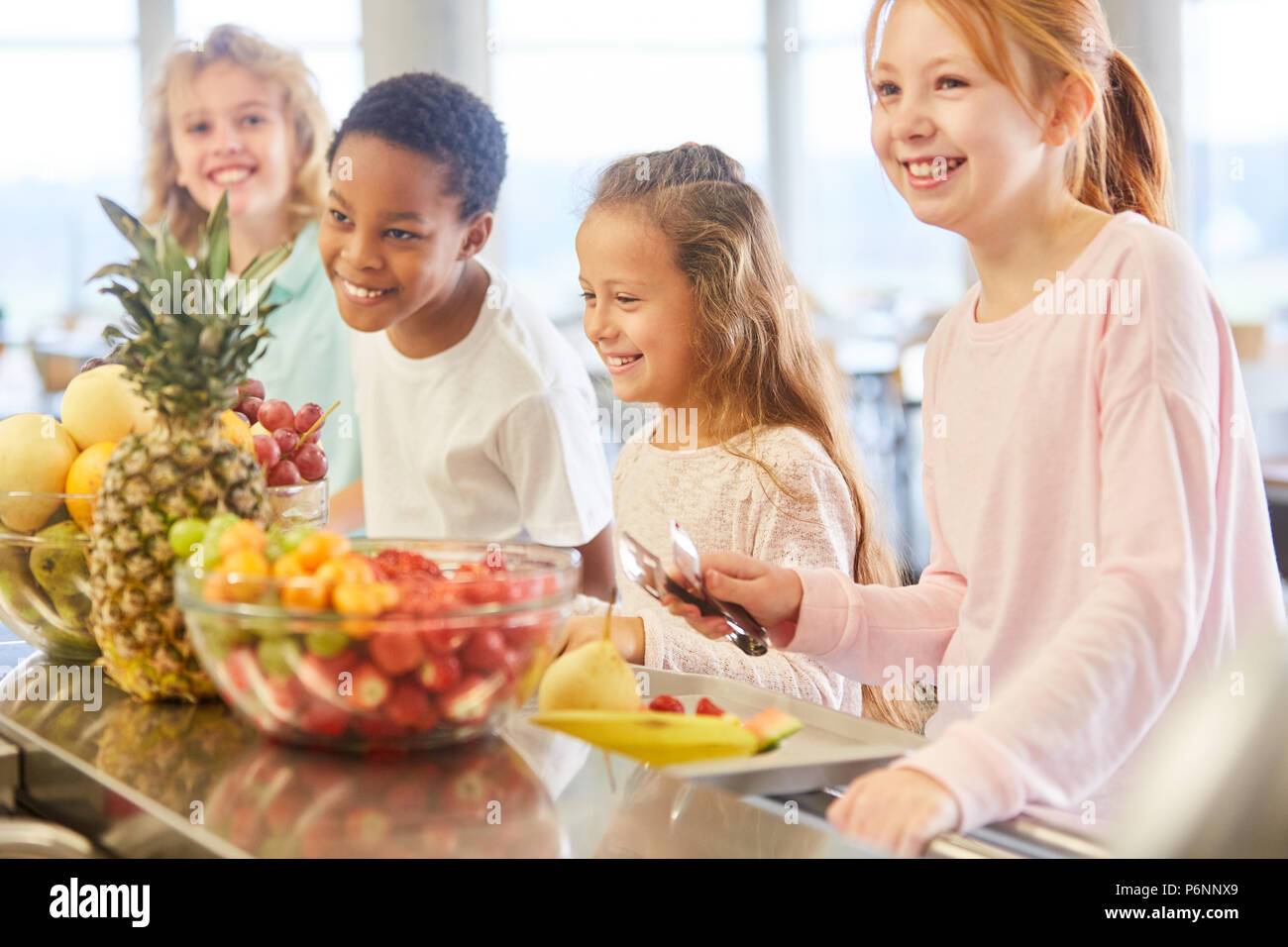 Children in multicultural school take healthy fruit in the canteen Stock Photo