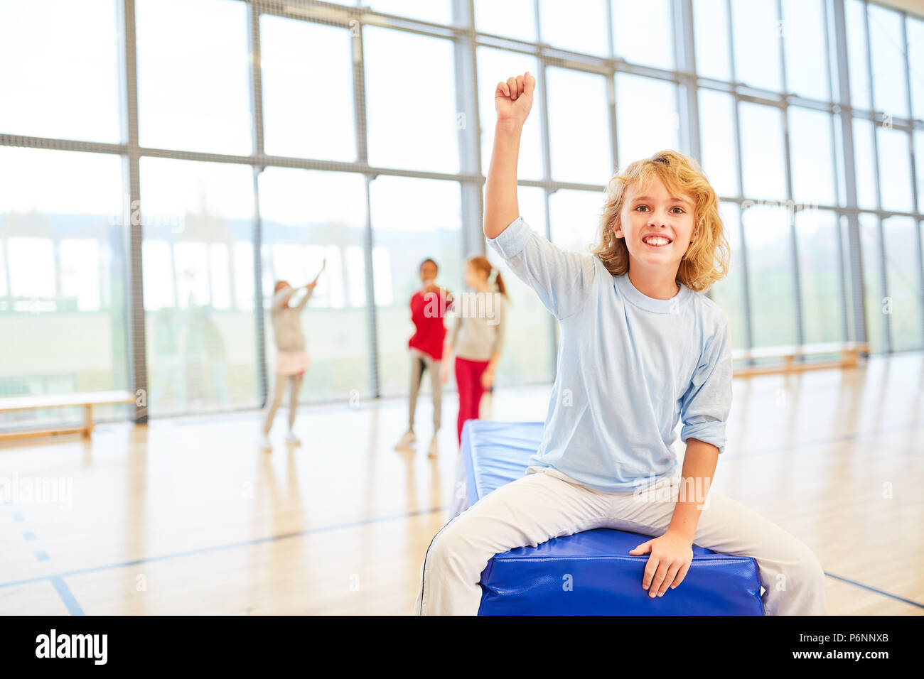 Happy boy is sitting at sports class in a primary school gym Stock Photo