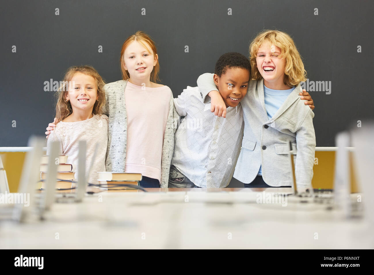 Four children as friends in multicultural elementary school are having fun Stock Photo