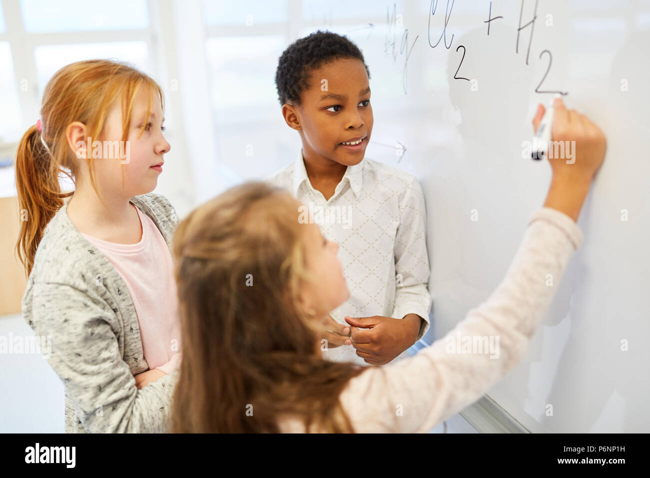 Group of kids in math lesson calculates a task on the blackboard Stock Photo