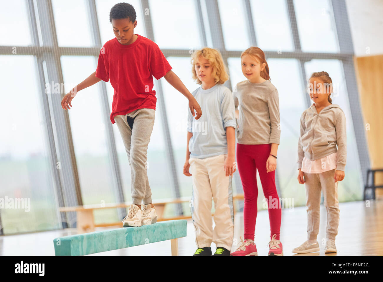 Children do gymnastics at the balance beam in primary school physical education Stock Photo