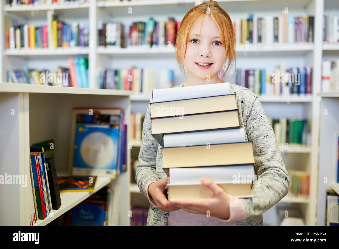 Hardworking girl as a pupil with a stack of books in the library Stock Photo