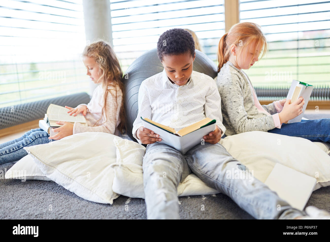 Group of children together read books in a primary school reading room Stock Photo
