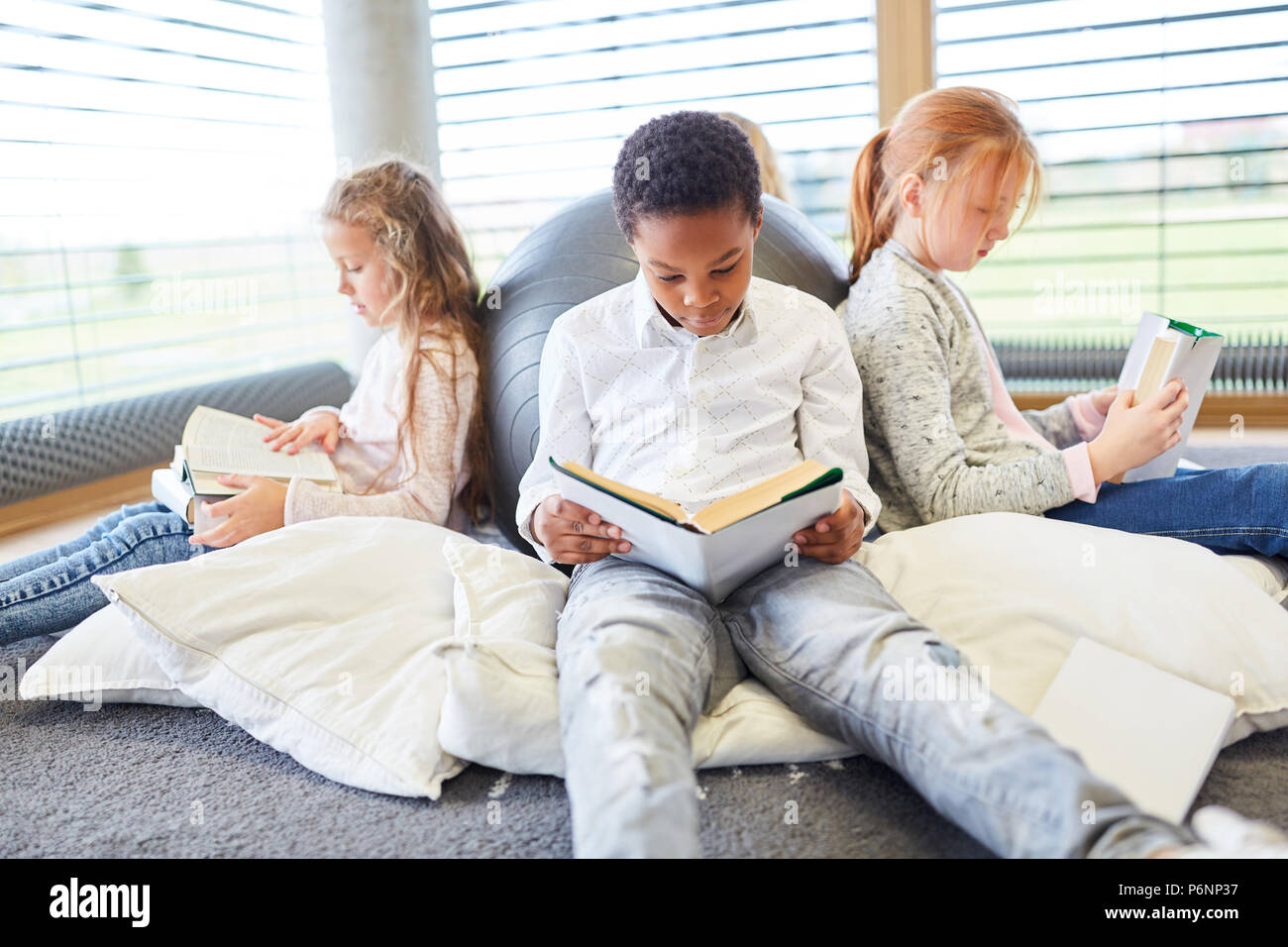 Group of children together read books in a primary school reading room ...