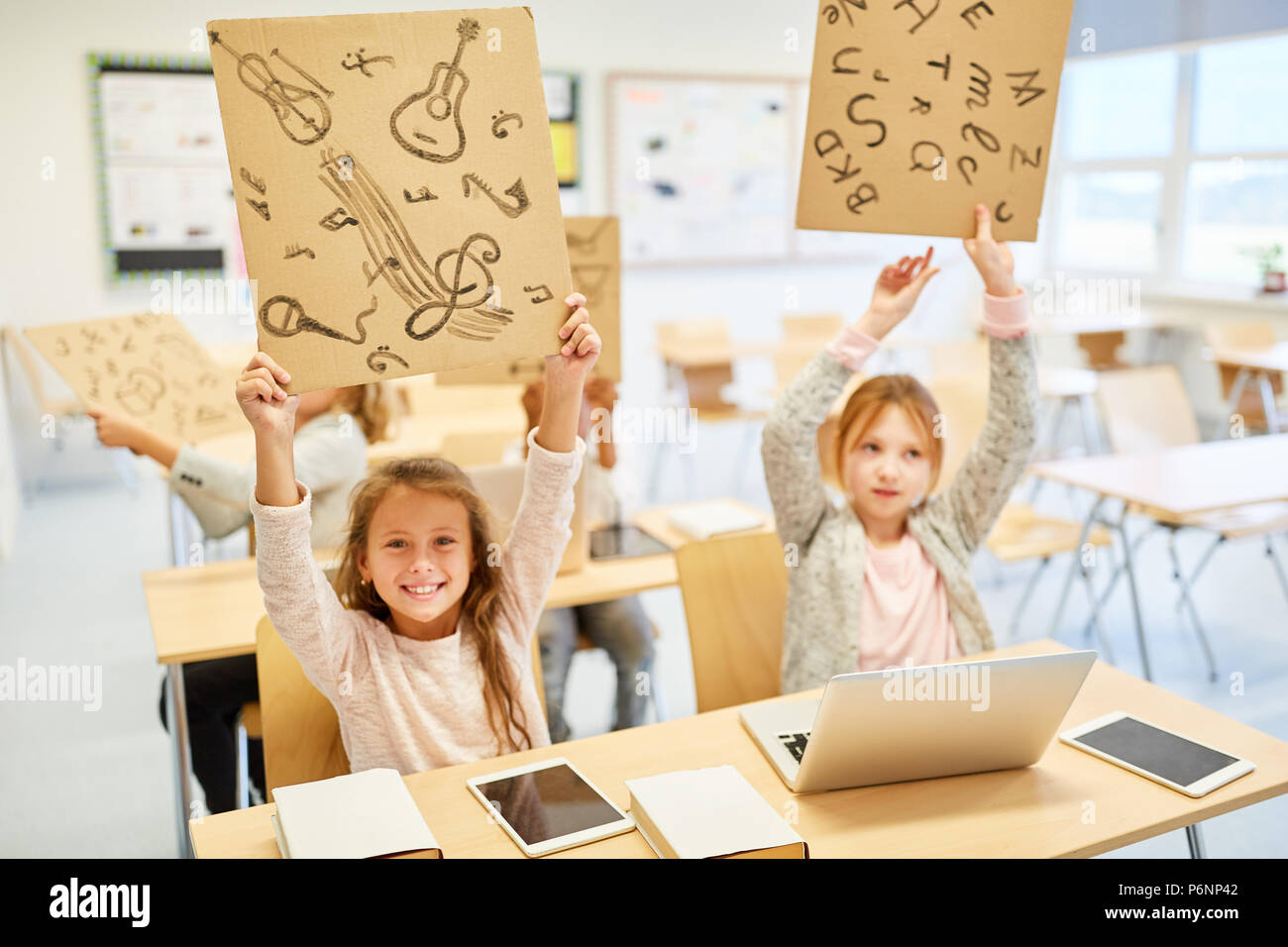 Girls in elementary school hold signs for creativity and music lessons Stock Photo