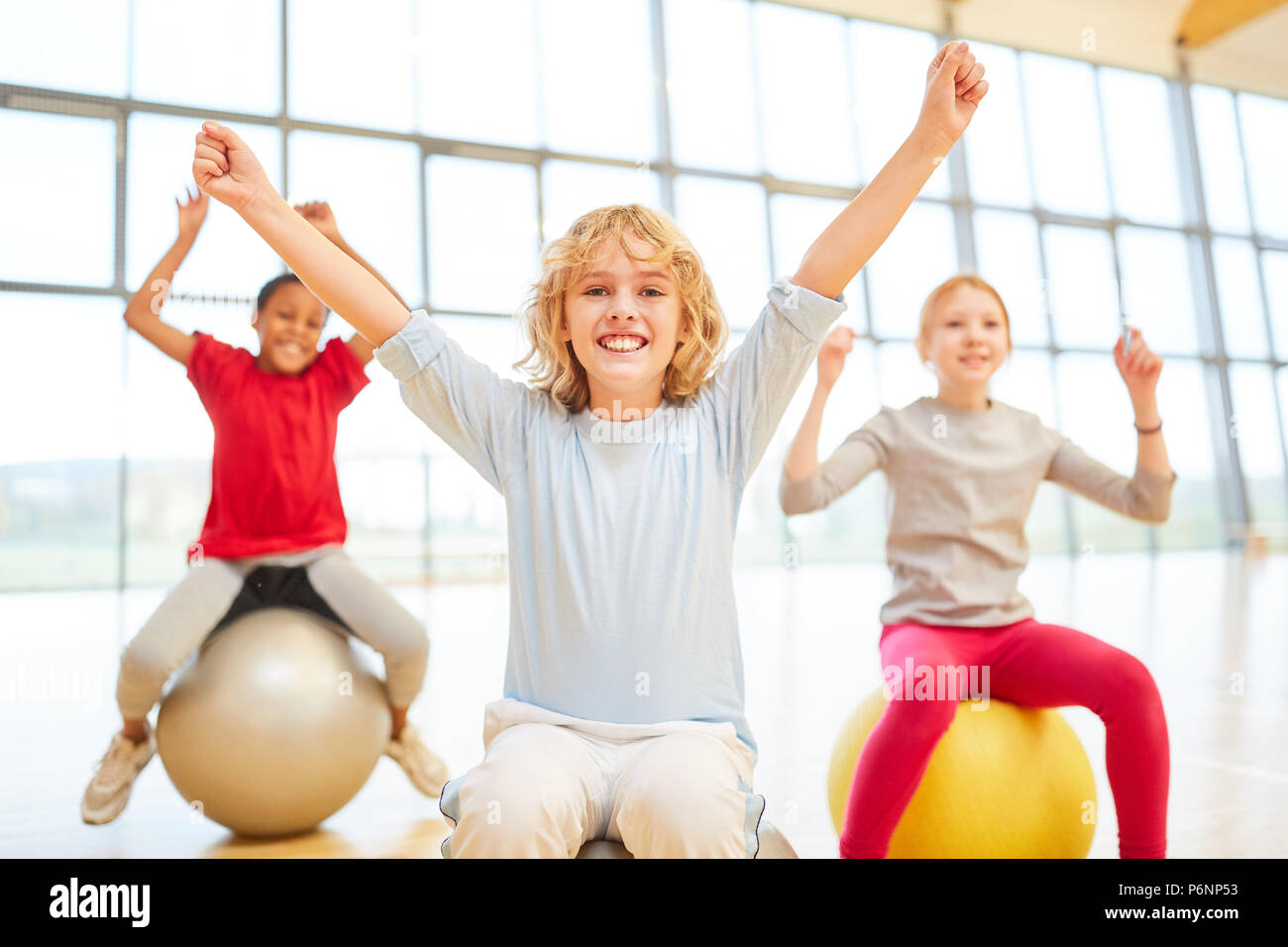 Cheering group of kids with bouncy ball in elementary school physical education Stock Photo