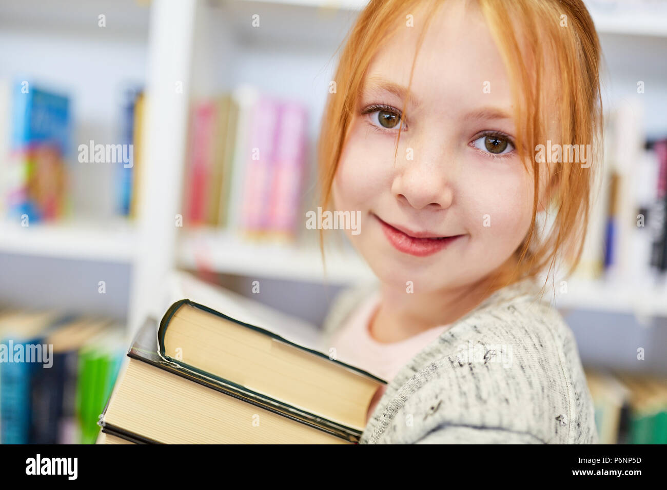Girl as a student in the library of the school borrows many books Stock Photo